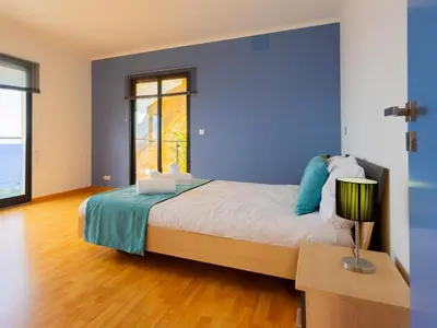 a bedroom with a bed with a blue wall at Skyline Villas Top in Arco da Calheta