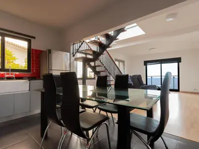 a dining room with a glass table and black chairs at Skyline Villas Top in Arco da Calheta