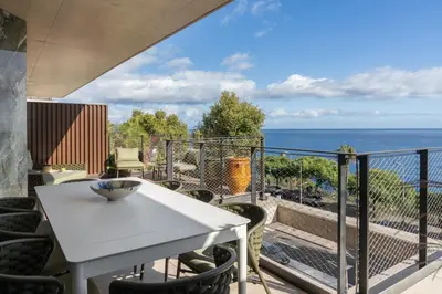 a white table and chairs on a balcony with the ocean at Savoy Monumentalis VIII by An Island Apart in Funchal