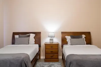a bedroom with two beds and a night stand with a lamp at Relax Garden House by An Island Apart in Arco da Calheta