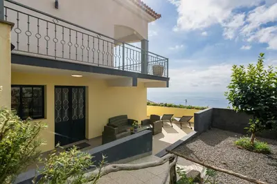 a house with a balcony with a view of the ocean at Relax Garden House by An Island Apart in Arco da Calheta