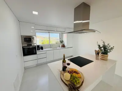 a white kitchen with a bowl of fruit on a counter at Atlantic View in Arco da Calheta