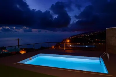 a swimming pool on the roof of a building at night at Atlantic View in Arco da Calheta