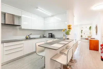 a kitchen with white cabinets and a large island with chairs at Topaz Scape Garajau Madeira by GRM in Caniço