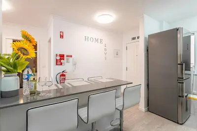 a kitchen with a counter with chairs and a refrigerator at Topaz Scape Garajau Madeira by GRM in Caniço