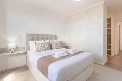 a white bedroom with a large bed with towels on it at Topaz Scape Garajau Madeira by GRM in Caniço
