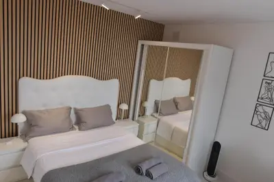 a white bedroom with a bed and a mirror at Casa da Vista Infinita in Ponta Delgada