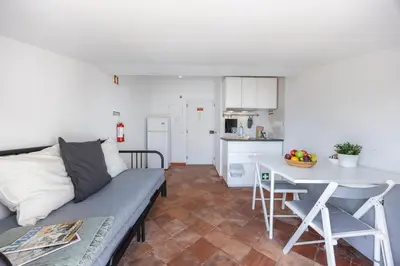 a living room with a couch and a table and a kitchen at Estúdio Praia da Luz in Luz