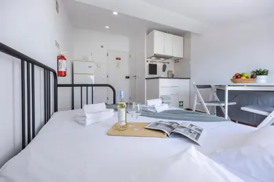 a white room with a bed and a table with a book at Estúdio Praia da Luz in Luz