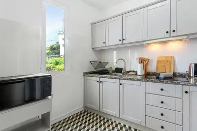 a kitchen with white cabinets and a sink and a window at Casa Da Avó Ferreirinha in Seixal