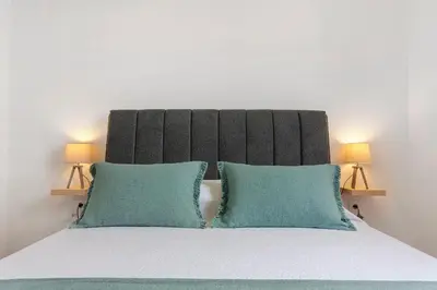 a bed with two green pillows and two lamps at Casa Da Avó Ferreirinha in Seixal
