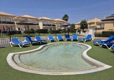 a swimming pool with blue chairs and chairs in a yard at Apartamento em Luxury Golf Resort in Lagos