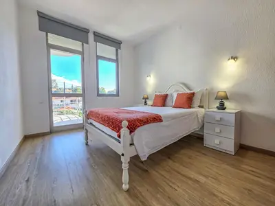 a white bedroom with a bed and a window at Blue Ship Residence in Funchal
