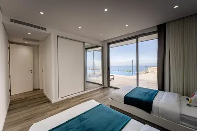 a bedroom with two beds and a view of the ocean at Villa Matias - Private pool and family comfort in Arco da Calheta