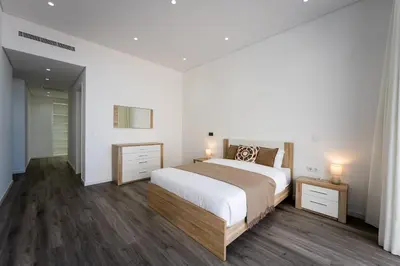 a white bedroom with a large bed and wooden floors at Villa Matias - Private pool and family comfort in Arco da Calheta