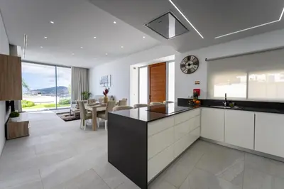 a kitchen with white cabinets and a dining room at Villa Matias - Private pool and family comfort in Arco da Calheta