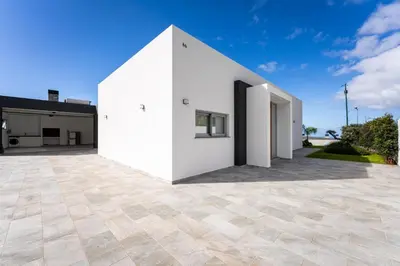a white house with a large patio at Villa Matias - Private pool and family comfort in Arco da Calheta