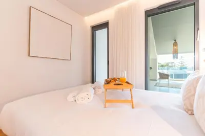 a bedroom with a white bed with a wooden table at Acqua Beach by Atlantic Holiday in Panasqueira