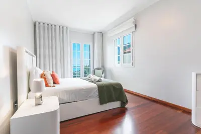 a white bedroom with a bed and two windows at Villa Alves by Altlantic Holiday in Faial