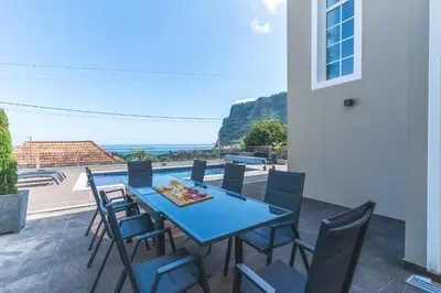 a table and chairs on a patio with a view of the ocean at Villa Alves by Altlantic Holiday in Faial