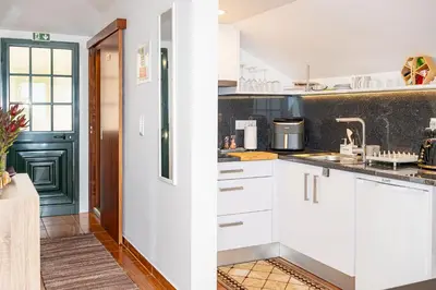 a kitchen with white cabinets and a green door at Horizonte Azul in Ponta do Sol