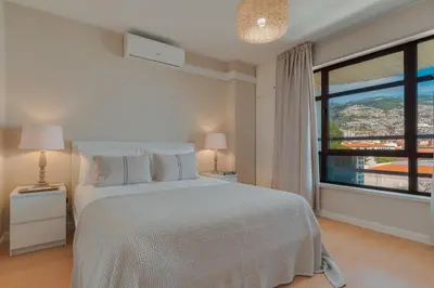 a bedroom with a white bed and a large window at Upgrade Paradise Marina in Funchal