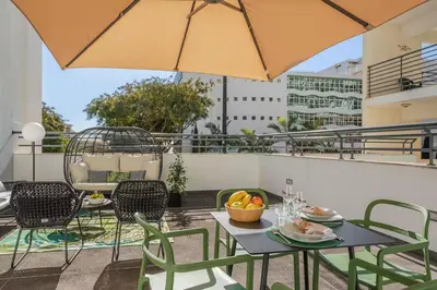 a patio with a table and chairs and an umbrella at Lido Ocean View - Perto da Praia com Estacionamento Privado in Funchal