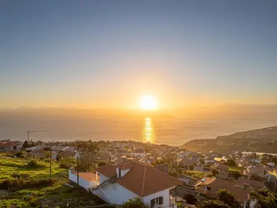 a sunset over a town with houses and the ocean at Villa Mirage - by Madeira To Stay in Arco da Calheta