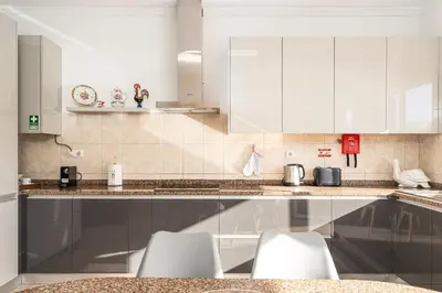 a kitchen with white cabinets and white stools at Villa Mirage - by Madeira To Stay in Arco da Calheta