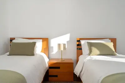 a bedroom with two beds and a table with a lamp at Villa Mirage - by Madeira To Stay in Arco da Calheta