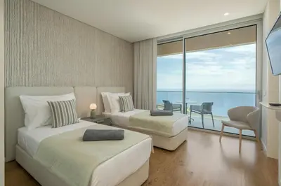 a bedroom with two beds and a view of the ocean at OurMadeira - GrandView Cristo Rei in Caniço