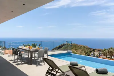 a balcony with a table and chairs overlooking the ocean at OurMadeira - GrandView Cristo Rei in Caniço