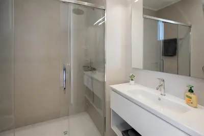 a white bathroom with a shower and a sink at OurMadeira - GrandView Cristo Rei in Caniço