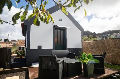 a small white house with a green door and chairs at Casa Serafina by Rent-a-key in Santa Maria Madalena