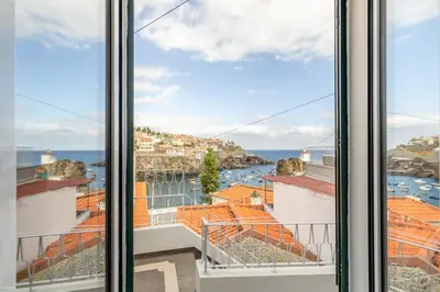 a view of the ocean from a window at Bay View Traditional house in city center in Câmara de Lobos
