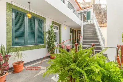a house with green shutters and potted plants at Bay View Traditional house in city center in Câmara de Lobos
