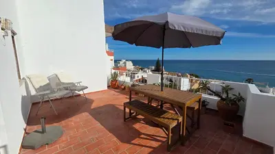 a patio with a wooden table and an umbrella at Margarida Seaview Terrace Apartment in Luz