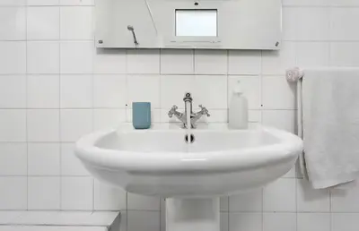a white sink in a white tiled bathroom at Machico Bay in Machico