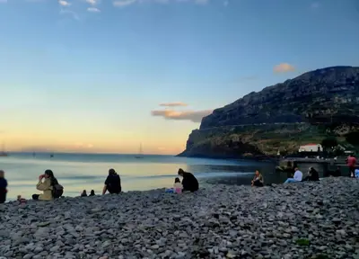 a group of people sitting on a rocky beach at Machico Bay in Machico