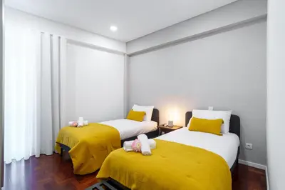 a bedroom with two beds with yellow sheets at Carmo Downtown Apartment by Amazing Madeira in Funchal