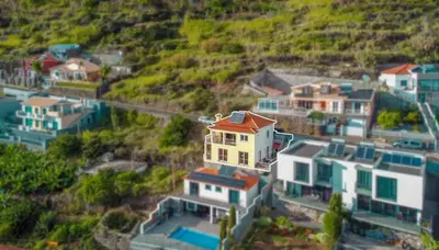 a group of cars parked on a street next to the ocean at Villa Casanova in Arco da Calheta