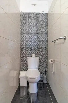a bathroom with a white toilet and a rug at Villa Casanova in Arco da Calheta