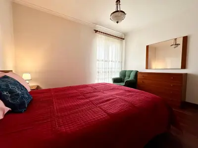 a bedroom with a red bed and a green chair at Lido Funchal in Funchal