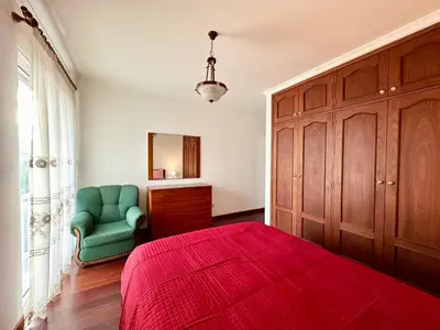 a bedroom with a red bed and a green chair at Lido Funchal in Funchal