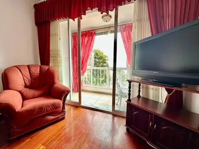 a living room with a chair and a flat screen tv at Lido Funchal in Funchal