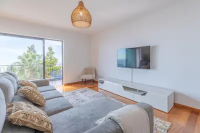 a living room with a couch and a tv at Sea View Apartment in Caniço