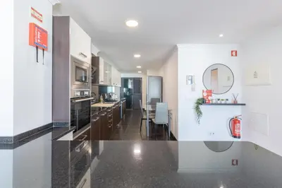 a kitchen with white walls and a black floor at Sea View Apartment in Caniço