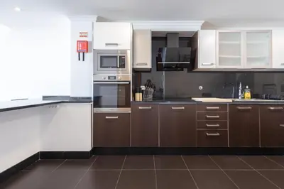 a kitchen with white appliances and brown cabinets at Sea View Apartment in Caniço