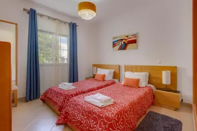 a bedroom with two beds with red sheets and a window at Beachside oasis with Pool in Luz