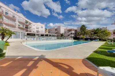 a swimming pool with palm trees and buildings at Beachside oasis with Pool in Luz